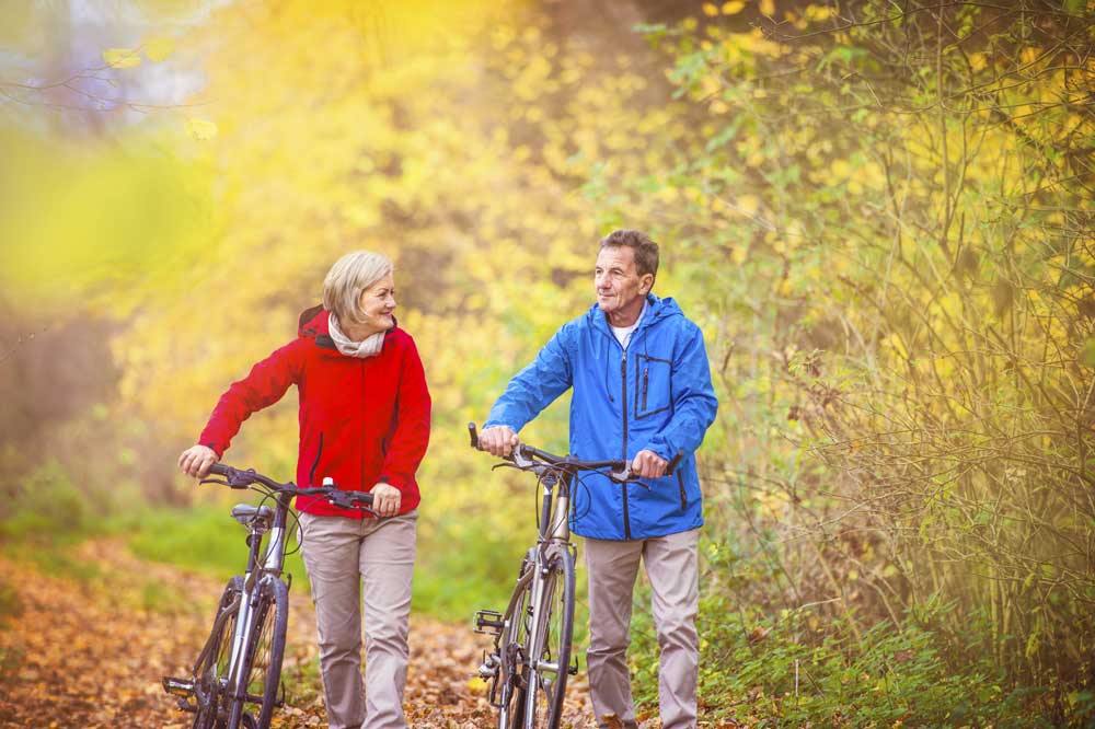 retired couple walking bikes